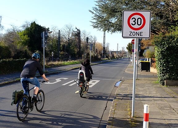 Infrastruktur_NRW_Bonn_ADFC_NRW__30 Zwei Radfahrer fahren an einem Tempo 30 Schild vorbei.