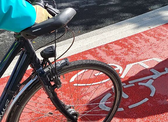 2023-08_LHA-Exkursion_MG_ADFC_NRW__23_.jpg Neu markierter Radfahrstreifen mit flächiger Roteinfärbung. Man sieht auch einen Fahrradlenker.