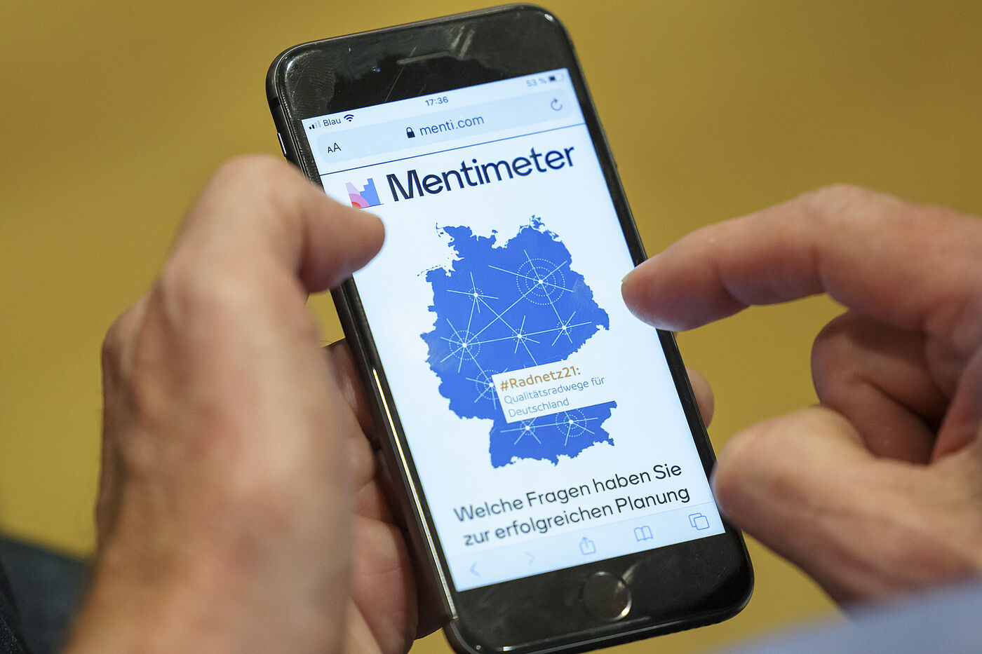 ADFC | Parlamentarischer Abend des ADFC Bundesverband | #Radnetz21: Mann hält ein Handy. Auf dem Handy ist die App Mentimeter zu sehen.